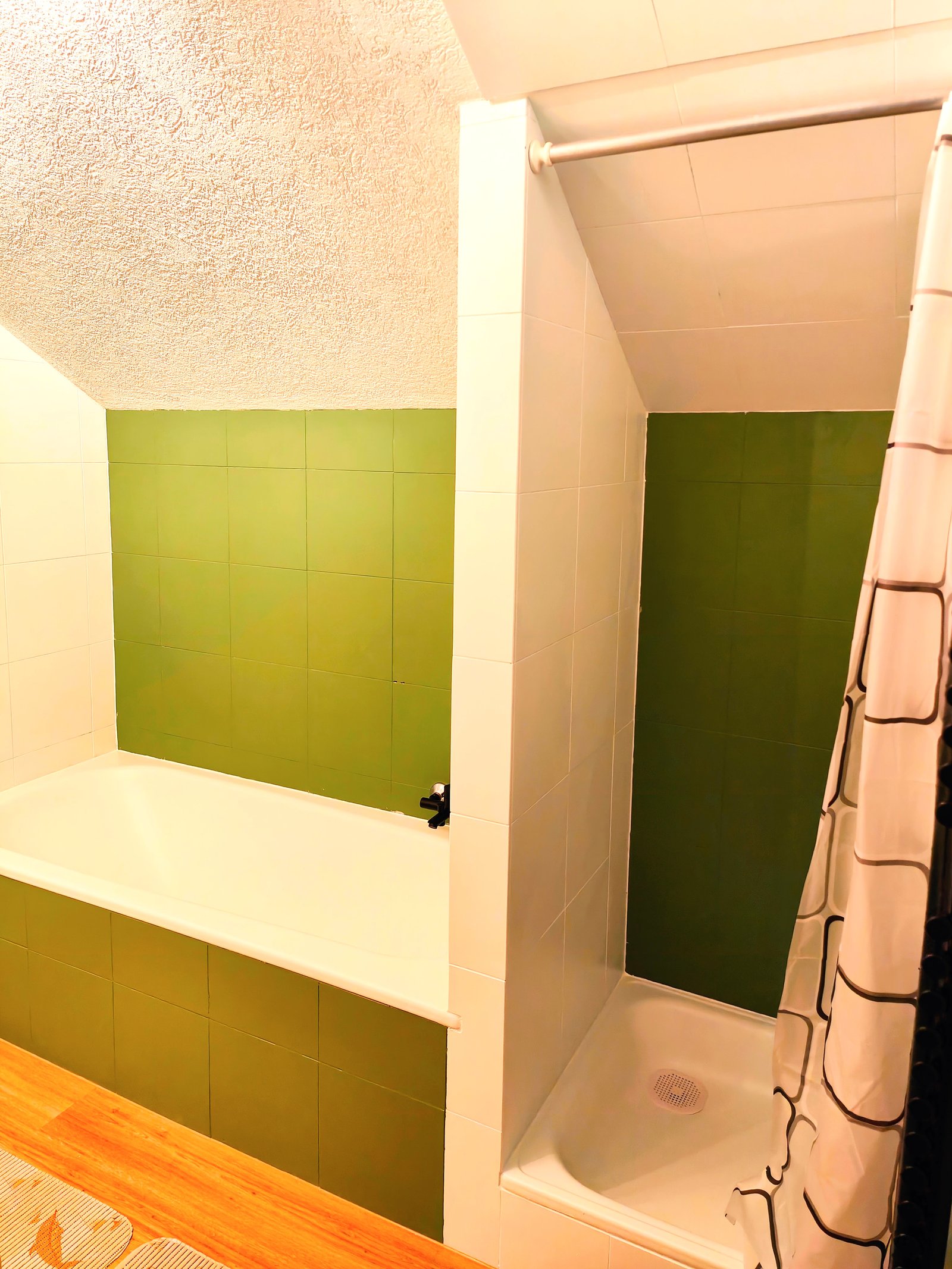 Badezimmer mit Badewanne und separater Duschkabine, akzentuiert mit grünen Fliesen