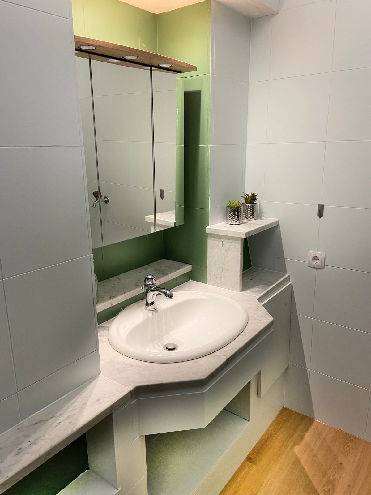 Waschtisch mit großem Spiegel und Marmoroptik im Badezimmer
